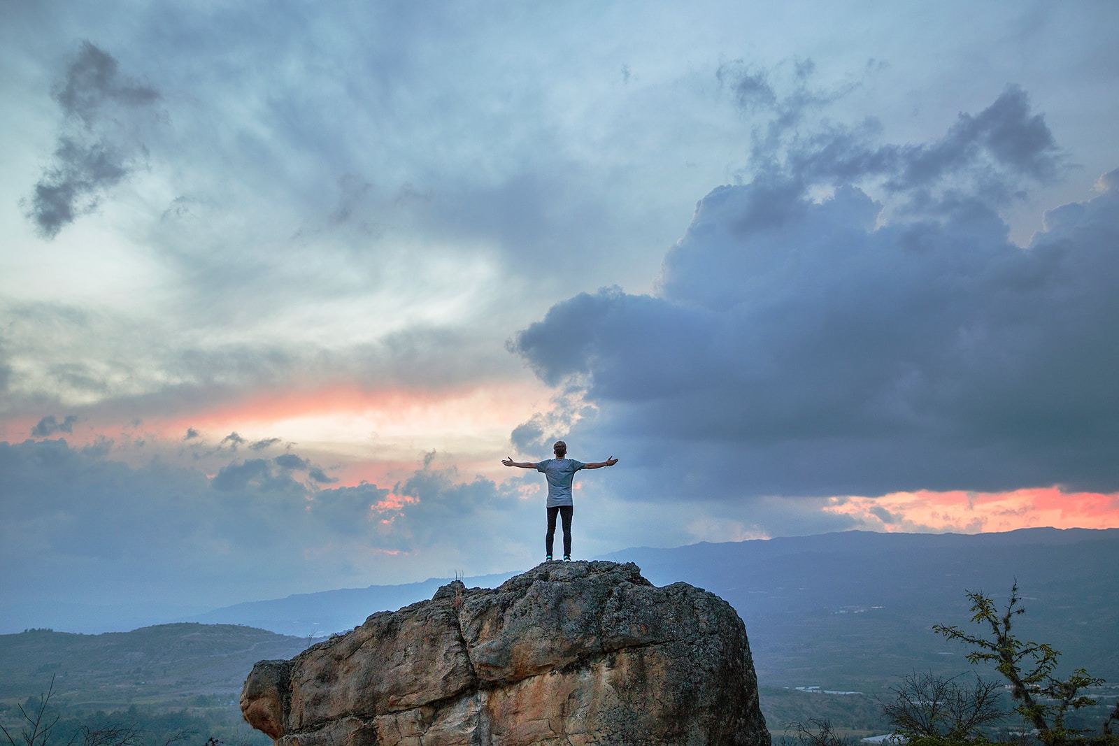 man standing on top of rock mountain after landing his next Product Management job